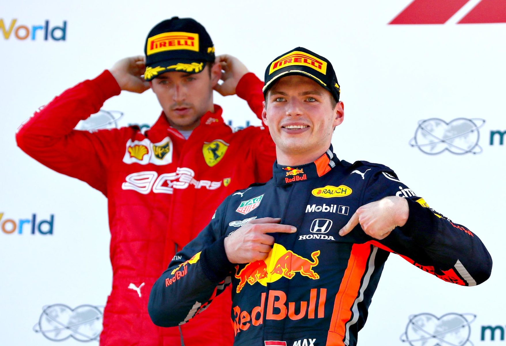 Max Verstappen points to the Honda logo on his overalls from the Austrian GP podium.