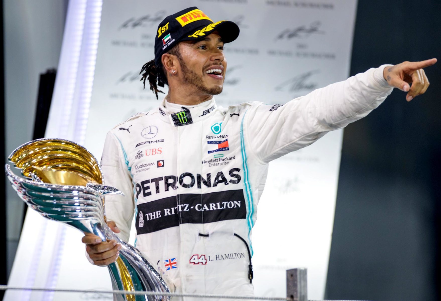 Lewis Hamilton holds the winners trophy on the Abu Dhabi GP podium and points into the crowd in celebration..